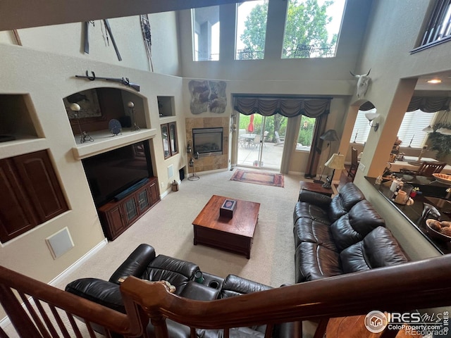 1402 Westfield Dr, Fort Collins, CO 80526 - carpeted living area featuring built in shelves, plenty of natural light, a high ceiling, and a tile fireplace