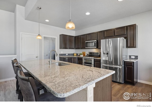 660 Cimarron Trl, Ault, CO 80610 - kitchen with appliances with stainless steel finishes, dark brown cabinetry, dark wood-style flooring, light stone counters, and decorative light fixtures