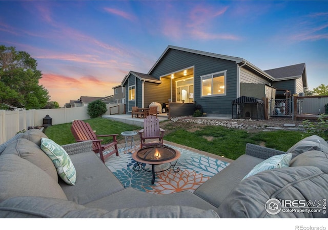 660 Cimarron Trl, Ault, CO 80610 - back of house at dusk with an outdoor living space with a fire pit, a patio area, a gate, and a fenced backyard
