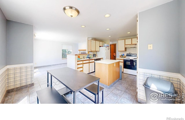 2027 Churchill Ct, Fort Collins, CO 80526 - kitchen featuring white appliances, a center island, wainscoting, light countertops, and under cabinet range hood