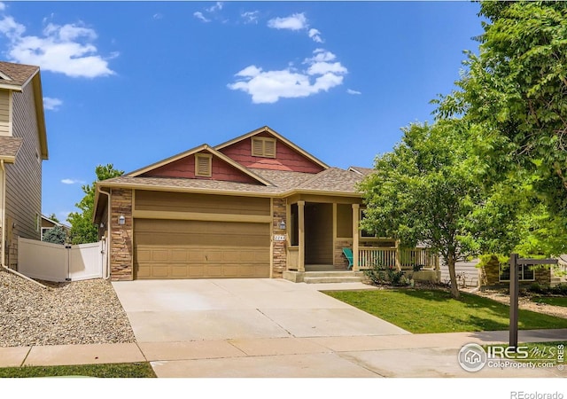 2244 Woodbury Ln, Fort Collins, CO 80524 - ranch-style home with driveway, an attached garage, covered porch, stone siding, and roof with shingles