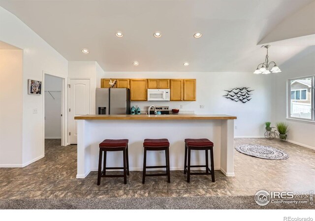 2244 Woodbury Ln, Fort Collins, CO 80524 - kitchen with stainless steel refrigerator with ice dispenser, white microwave, a kitchen bar, brown cabinets, and a chandelier