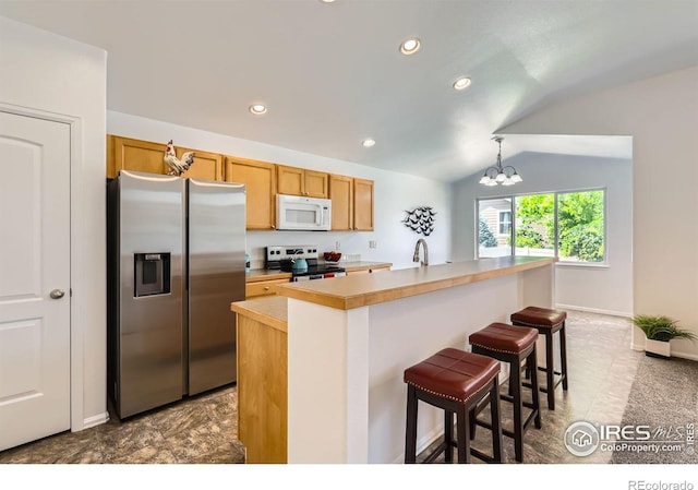 2244 Woodbury Ln, Fort Collins, CO 80524 - kitchen featuring appliances with stainless steel finishes, vaulted ceiling, recessed lighting, light countertops, and a kitchen breakfast bar