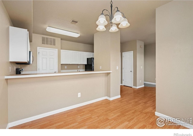 6925 19th St Unit 15, Greeley, CO 80634 - kitchen featuring freestanding refrigerator, a chandelier, light wood-style flooring, white cabinets, and a peninsula