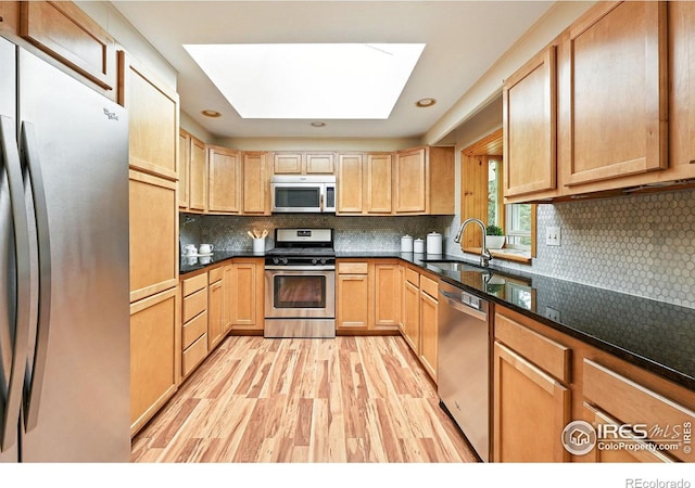 775 Pleasant St, Boulder, CO 80302 - kitchen with appliances with stainless steel finishes, a skylight, light wood finished floors, decorative backsplash, and light brown cabinets