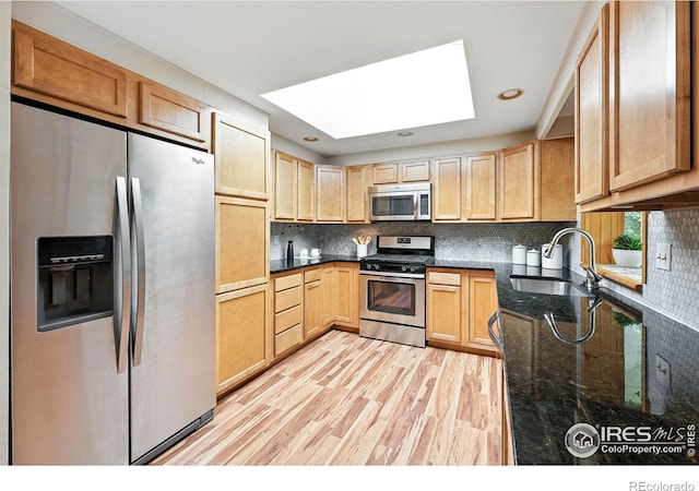 775 Pleasant St, Boulder, CO 80302 - kitchen with stainless steel appliances, a skylight, dark stone counters, decorative backsplash, and light wood-style floors
