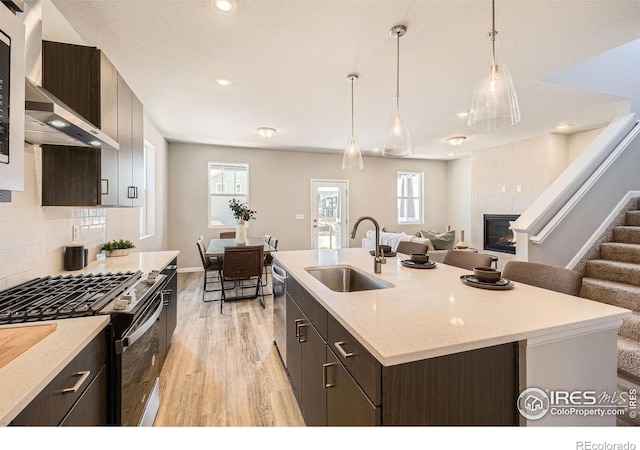 2290 Walbridge Rd, Fort Collins, CO 80524 - kitchen with appliances with stainless steel finishes, wall chimney exhaust hood, light wood finished floors, a tile fireplace, and open floor plan