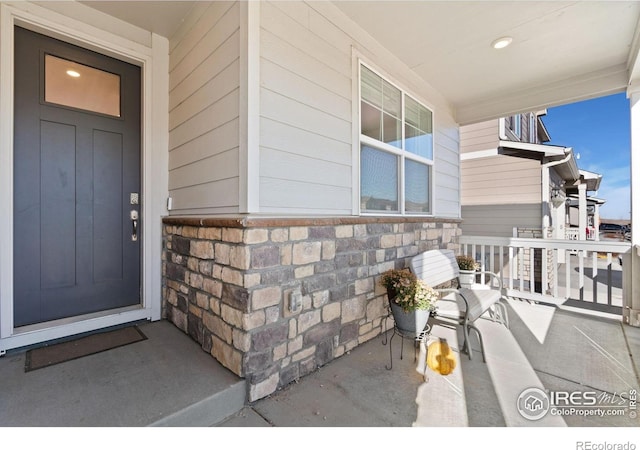 9873 Ceylon St, Commerce City, CO 80022 - doorway to property featuring a porch and stone siding