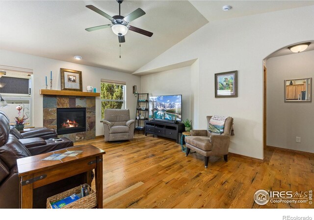 1613 Alpine Ave, Berthoud, CO 80513 - living area featuring vaulted ceiling, ceiling fan, light wood-style flooring, a tiled fireplace, and arched walkways