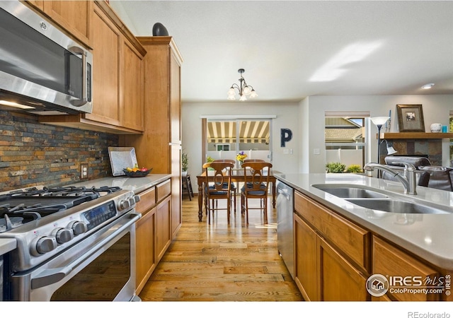 1613 Alpine Ave, Berthoud, CO 80513 - kitchen with stainless steel appliances, light wood-style flooring, tasteful backsplash, brown cabinets, and light countertops