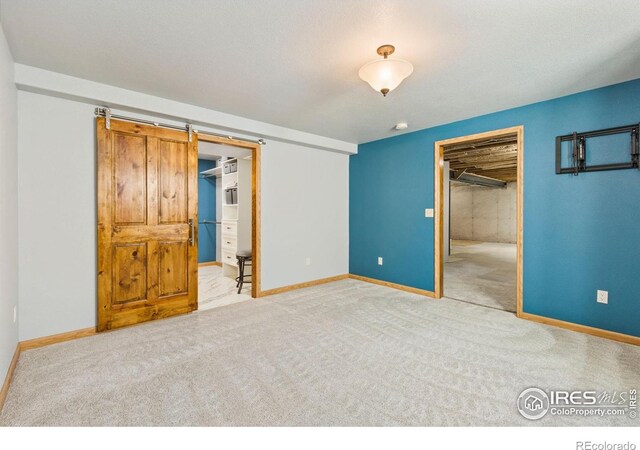 1613 Alpine Ave, Berthoud, CO 80513 - unfurnished bedroom featuring a walk in closet, a closet, carpet floors, and a barn door