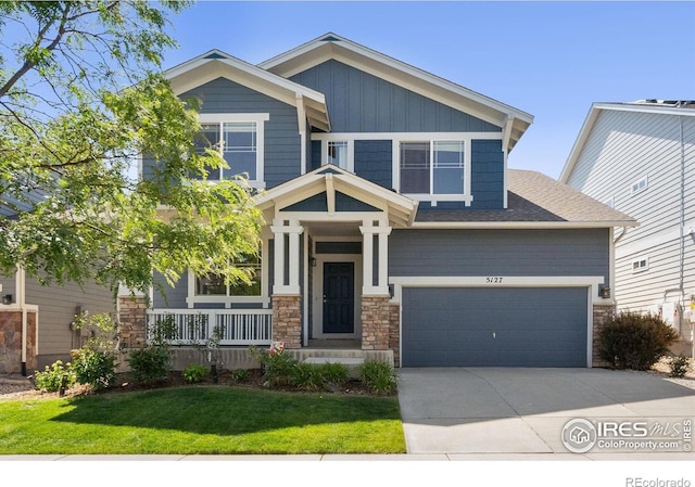 5127 Exploration Ln, Fort Collins, CO 80528 - craftsman-style home with stone siding, concrete driveway, covered porch, a front lawn, and an attached garage
