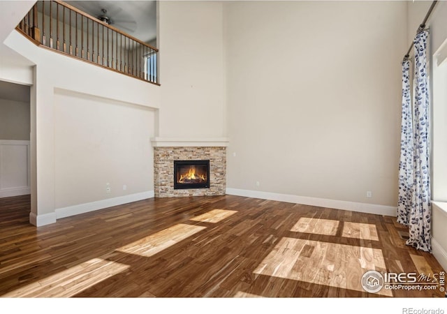 5127 Exploration Ln, Fort Collins, CO 80528 - unfurnished living room with wood finished floors, a towering ceiling, and a stone fireplace