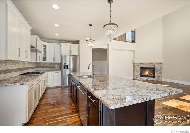 5127 Exploration Ln, Fort Collins, CO 80528 - kitchen with appliances with stainless steel finishes, dark wood finished floors, a chandelier, decorative backsplash, and glass insert cabinets