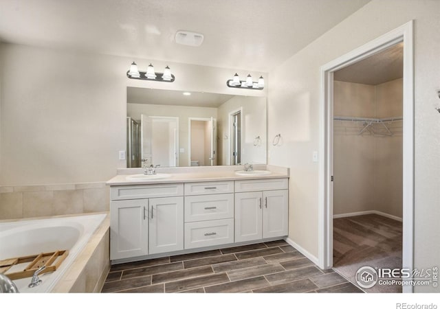 5127 Exploration Ln, Fort Collins, CO 80528 - full bath with double vanity, a garden tub, a walk in closet, wood finished floors, and an enclosed shower