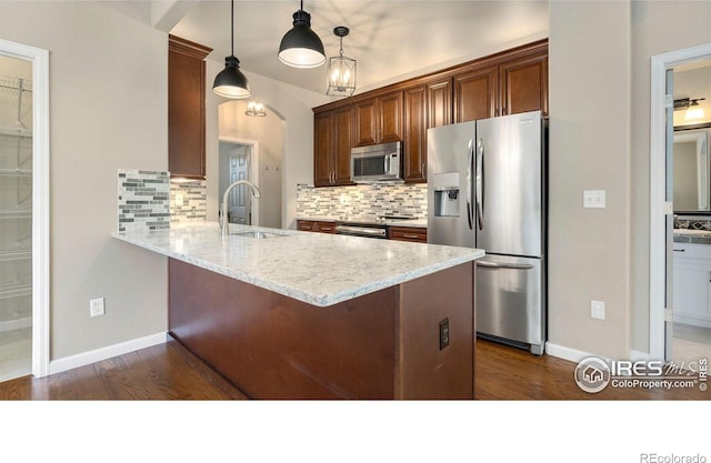 1937 Mahogany Way, Severance, CO 80550 - kitchen with appliances with stainless steel finishes, decorative backsplash, dark wood-type flooring, a peninsula, and light stone countertops