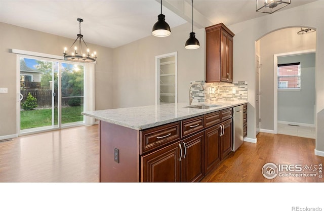 1937 Mahogany Way, Severance, CO 80550 - kitchen with a chandelier, light wood-style floors, arched walkways, and tasteful backsplash