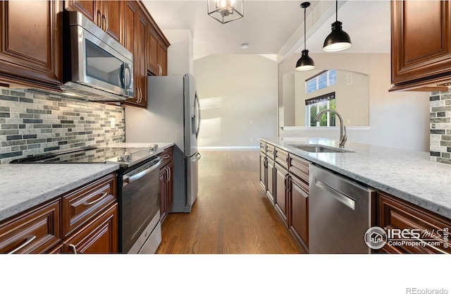 1937 Mahogany Way, Severance, CO 80550 - kitchen with appliances with stainless steel finishes, dark wood-style floors, backsplash, and decorative light fixtures