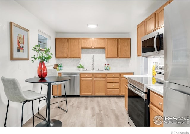 4240 Harlan St, Wheat Ridge, CO 80033 - kitchen with appliances with stainless steel finishes, backsplash, light countertops, and light wood-style floors