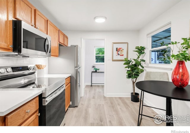 4240 Harlan St, Wheat Ridge, CO 80033 - kitchen with stainless steel appliances, light wood-style flooring, decorative backsplash, and light countertops