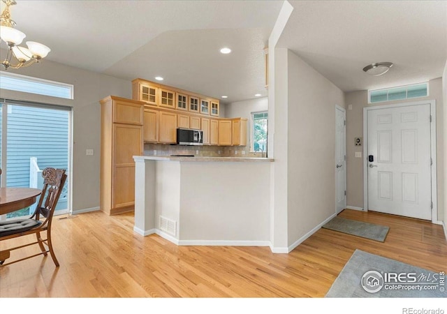 3632 Cassiopeia Ln, Fort Collins, CO 80528 - kitchen with stainless steel microwave, light brown cabinetry, light wood finished floors, a chandelier, and decorative backsplash