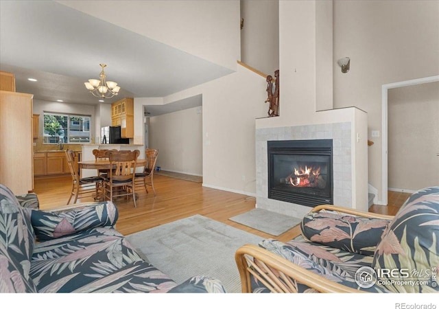 3632 Cassiopeia Ln, Fort Collins, CO 80528 - living area featuring a chandelier, light wood finished floors, a tiled fireplace, and a towering ceiling