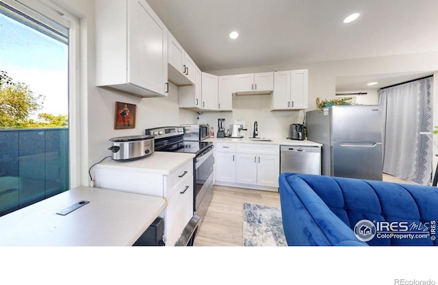 5326 Lowell Blvd, Denver, CO 80221 - kitchen with appliances with stainless steel finishes, white cabinetry, light countertops, recessed lighting, and light wood finished floors