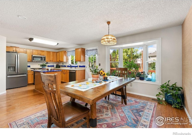 1026 Red Oak Dr, Longmont, CO 80504 - dining space featuring a chandelier, light wood-style floors, a textured ceiling, and plenty of natural light