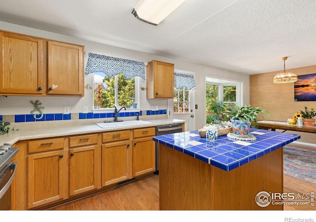 1026 Red Oak Dr, Longmont, CO 80504 - kitchen with tile counters, light wood finished floors, stainless steel appliances, healthy amount of natural light, and a textured ceiling
