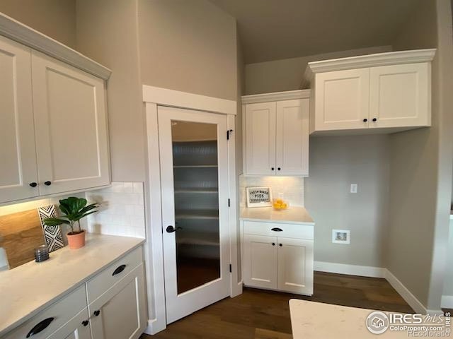 7156 Feather Reed Dr, Wellington, CO 80549 - kitchen with dark wood-style floors, white cabinets, tasteful backsplash, and light countertops