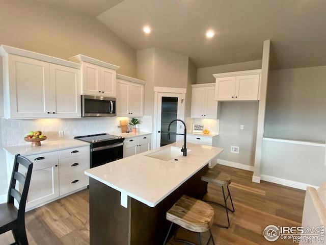 7156 Feather Reed Dr, Wellington, CO 80549 - kitchen with stainless steel appliances, tasteful backsplash, white cabinets, lofted ceiling, and light countertops