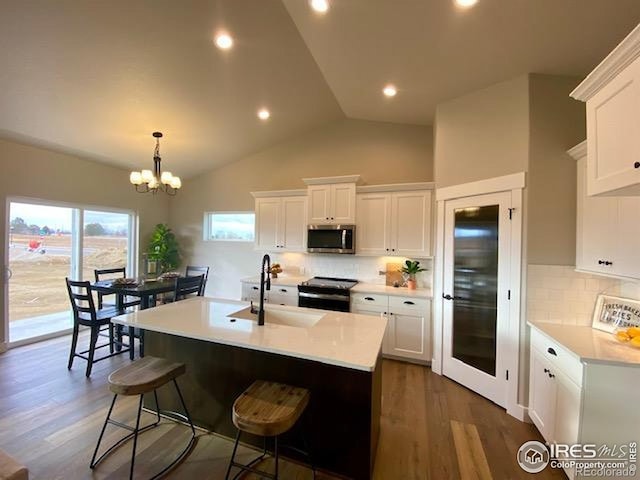 7156 Feather Reed Dr, Wellington, CO 80549 - kitchen featuring stainless steel microwave, black / electric stove, light countertops, white cabinets, and lofted ceiling