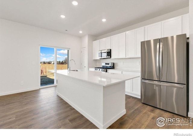 3178 Buffalo Grass Ln, Wellington, CO 80549 - kitchen with appliances with stainless steel finishes, an island with sink, dark wood-style floors, recessed lighting, and white cabinetry