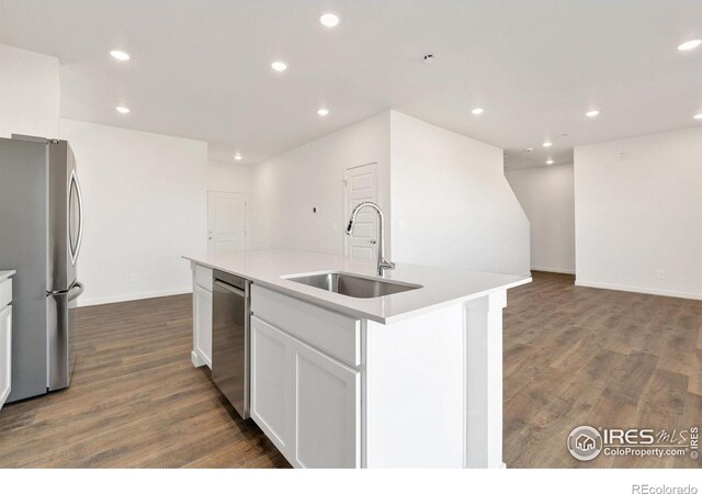 3178 Buffalo Grass Ln, Wellington, CO 80549 - kitchen with stainless steel appliances, dark wood-style flooring, a center island with sink, recessed lighting, and white cabinets