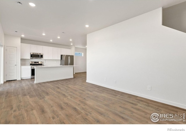 3178 Buffalo Grass Ln, Wellington, CO 80549 - kitchen featuring stainless steel appliances, recessed lighting, white cabinetry, open floor plan, and wood finished floors
