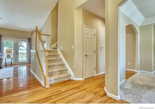 2408 Eagleview Cir, Longmont, CO 80504 - stairs featuring french doors, wood finished floors, arched walkways, and vaulted ceiling