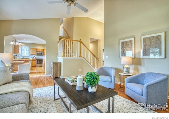2408 Eagleview Cir, Longmont, CO 80504 - living room with ceiling fan, stairway, arched walkways, light wood-type flooring, and high vaulted ceiling