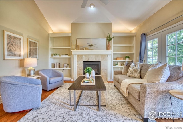 2408 Eagleview Cir, Longmont, CO 80504 - living area with a ceiling fan, built in features, a tile fireplace, wood finished floors, and vaulted ceiling