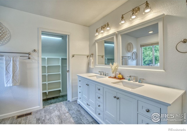 2408 Eagleview Cir, Longmont, CO 80504 - bathroom with double vanity, a walk in closet, and wood finished floors