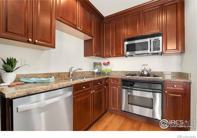 1827 N Grant St Unit 604, Denver, CO 80203 - kitchen featuring stainless steel appliances, light wood-style floors, and light stone counters