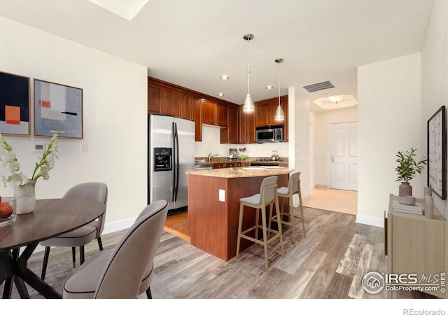 1827 N Grant St Unit 604, Denver, CO 80203 - kitchen with stainless steel appliances, light wood-style flooring, a kitchen island, a breakfast bar area, and decorative light fixtures