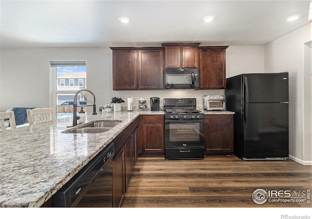 2065 Wildwood St, Lochbuie, CO 80603 - kitchen with black appliances, light stone countertops, dark wood-type flooring, dark brown cabinets, and a peninsula