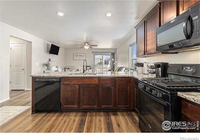 2065 Wildwood St, Lochbuie, CO 80603 - kitchen featuring black appliances, dark wood-type flooring, ceiling fan, a peninsula, and light stone countertops