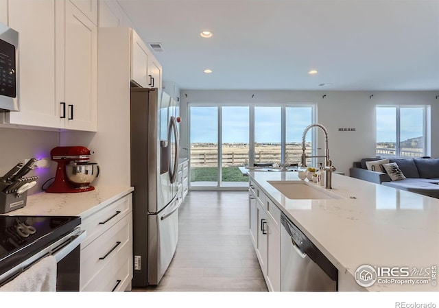 6645 Dry Fork Dr, Frederick, CO 80516 - kitchen with appliances with stainless steel finishes, white cabinets, light wood-style flooring, recessed lighting, and light stone countertops