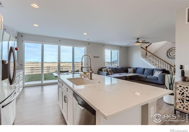 6645 Dry Fork Dr, Frederick, CO 80516 - kitchen featuring stainless steel appliances, light wood-style floors, a center island with sink, recessed lighting, and white cabinets