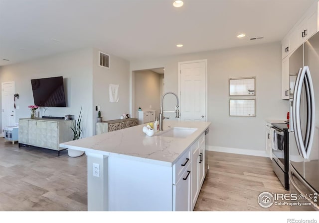 6645 Dry Fork Dr, Frederick, CO 80516 - kitchen with appliances with stainless steel finishes, light wood finished floors, white cabinets, light stone countertops, and a center island with sink