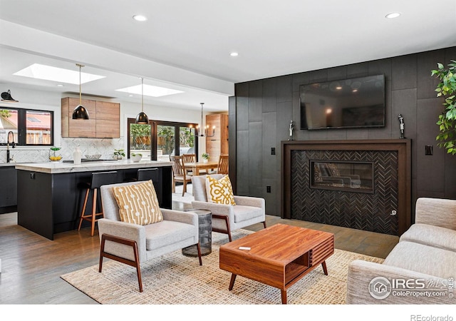 3275 19th St, Boulder, CO 80304 - living area featuring light wood-style floors, recessed lighting, a tiled fireplace, a skylight, and a chandelier