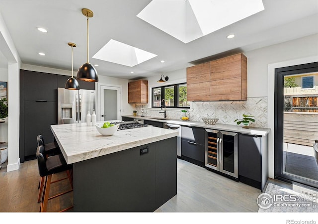3275 19th St, Boulder, CO 80304 - kitchen with a skylight, appliances with stainless steel finishes, wine cooler, light wood finished floors, and backsplash
