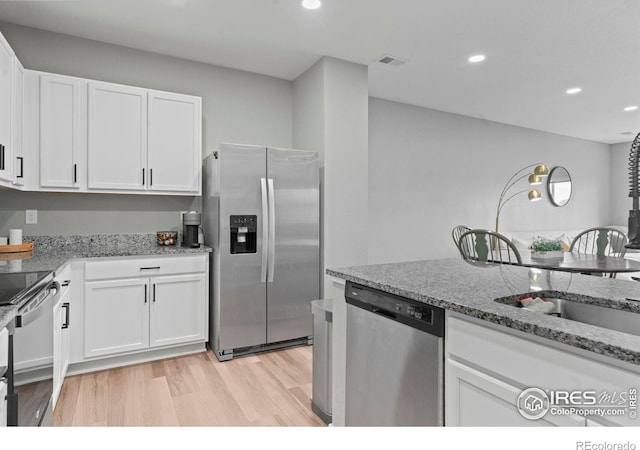 3644 Ronald Reagan Ave, Wellington, CO 80549 - kitchen featuring appliances with stainless steel finishes, white cabinets, recessed lighting, light stone countertops, and light wood finished floors