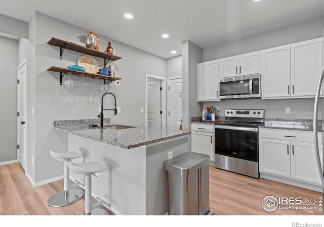 3644 Ronald Reagan Ave, Wellington, CO 80549 - kitchen featuring stainless steel appliances, white cabinetry, light wood-style floors, light stone counters, and open shelves